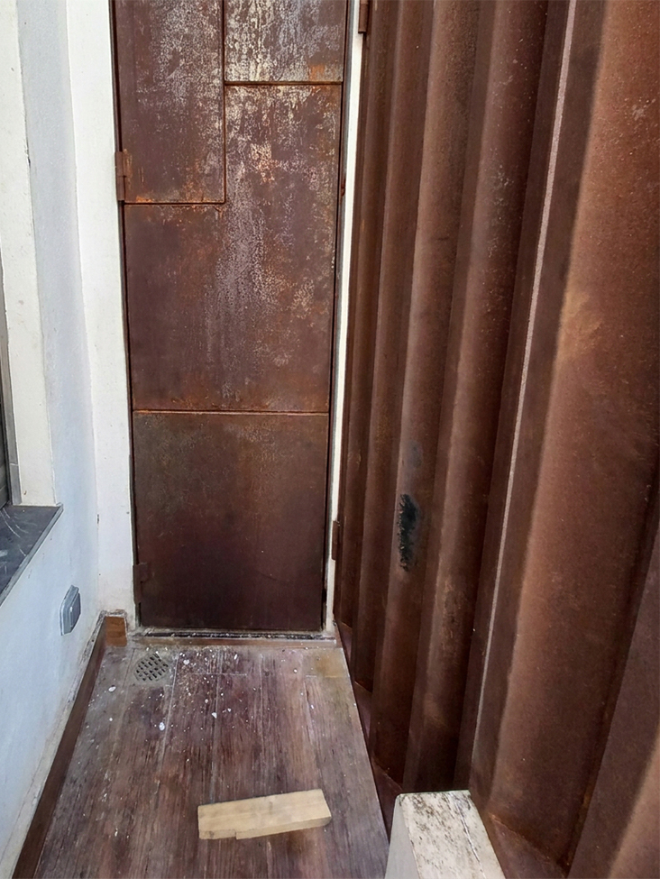 Habillage mural en acier Corten avec porte technique intégrée et panneaux métalliques nervurés