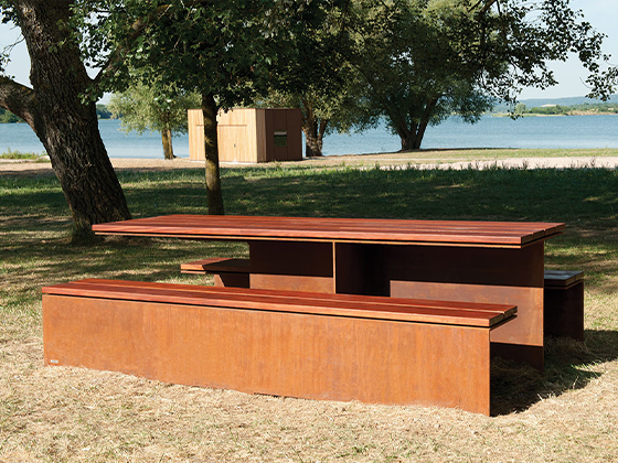 Table de pique-nique avec bancs en acier Corten et assises en bois dans un parc