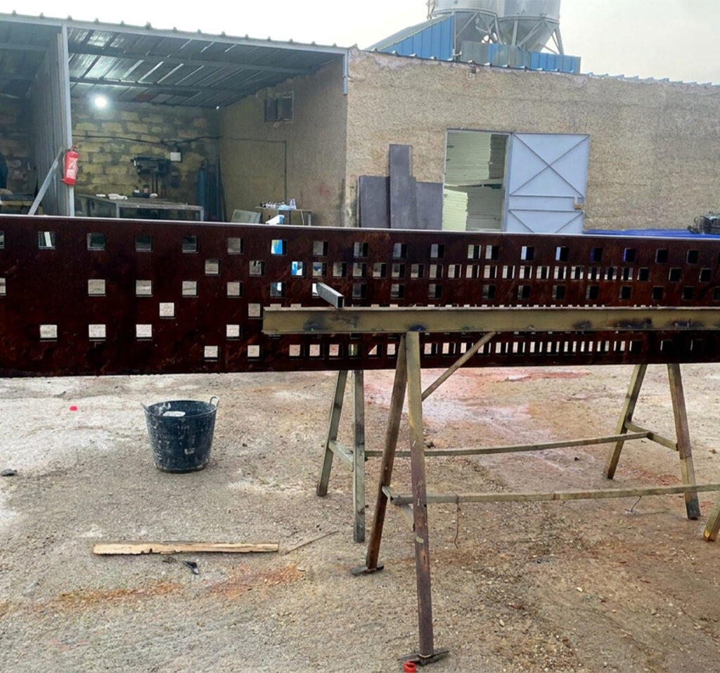 Panneau perforé en Acier Corten posé sur des supports pendant sa fabrication en atelier