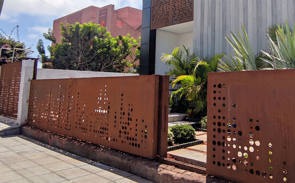 Portail coulissant et clôture perforée en Acier Corten installés devant une villa contemporaine
