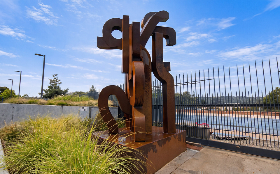 Sculpture abstraite monumentale en Acier Corten installée dans un aménagement paysager contemporain