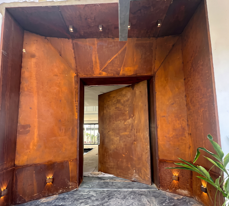 Entrée architecturale en acier Corten sur mesure avec porte pivotante et habillage mural