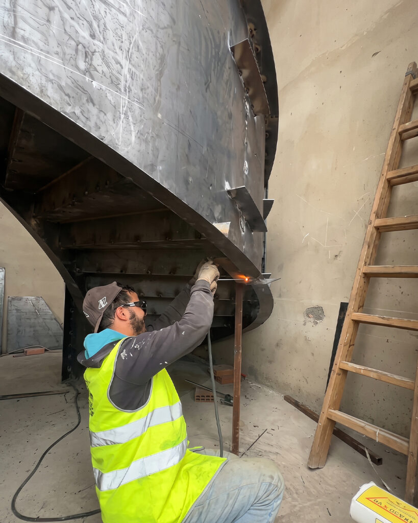 Professionnel assemblant une grande structure métallique courbe dans un Atelier acier Corten