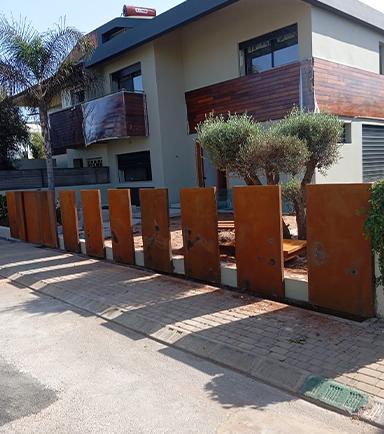 Clôture en panneaux d’acier réalisée dans le cadre d’une Fabrication Corten sur mesure devant une villa contemporaine