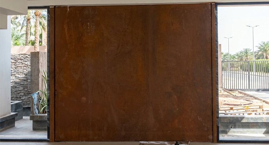 Fabrication Corten sur mesure d’une grande porte coulissante en acier patiné pour une entrée contemporaine