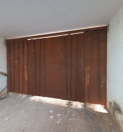Fabrication Corten sur mesure d’une grande porte de garage métallique composée de panneaux verticaux
