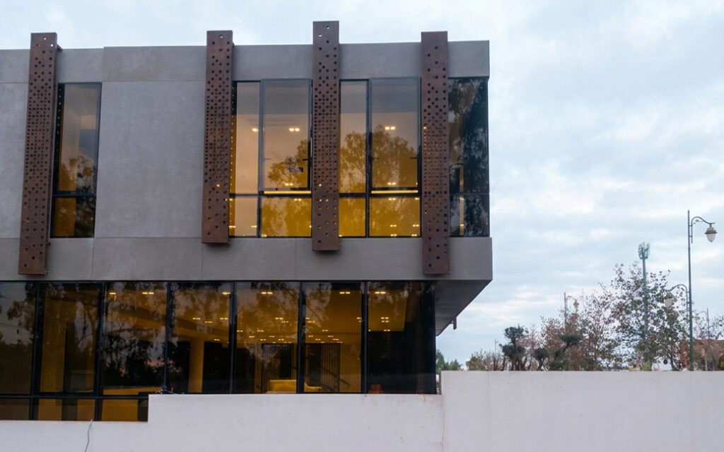 Panneaux verticaux perforés en acier Corten sur mesure installés sur la façade vitrée d’un bâtiment contemporain